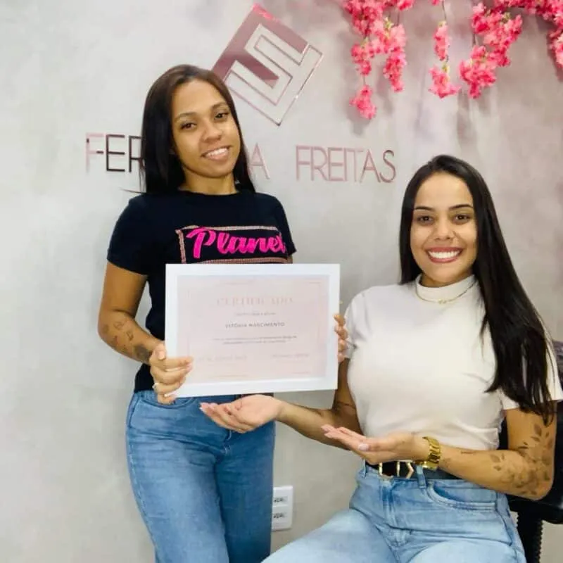Aluna formada recebendo certificado ao lado da Fernanda
